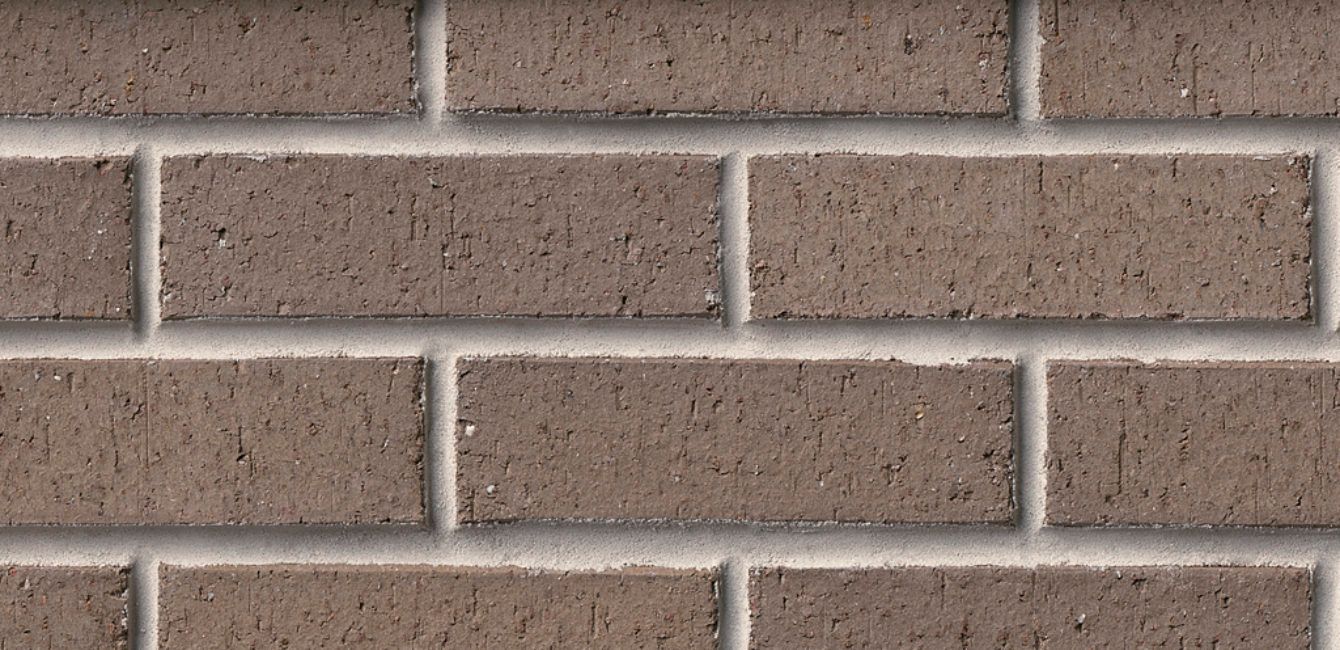 Close-up of a brick wall with gray mortar and brown bricks.