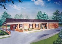 Brick building with dark roof, porch, and a driveway. Trees and blue sky in the background.