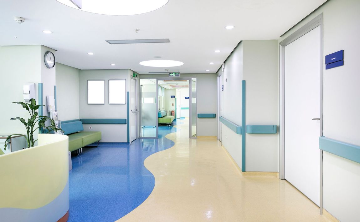 Un lungo corridoio in un ospedale con un pavimento blu e giallo.