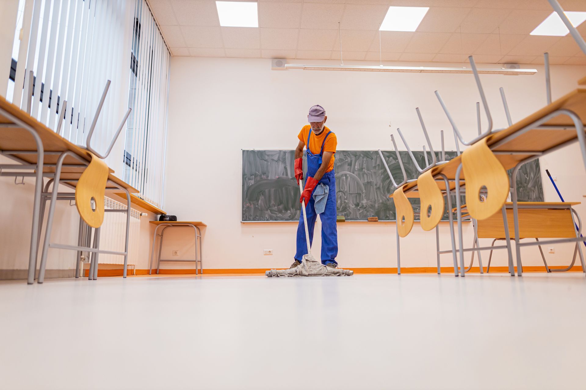 Un uomo sta lavando il pavimento di un'aula.