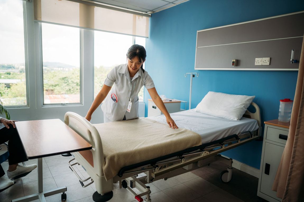 Un'infermiera sta rifacendo un letto d'ospedale in una stanza d'ospedale.