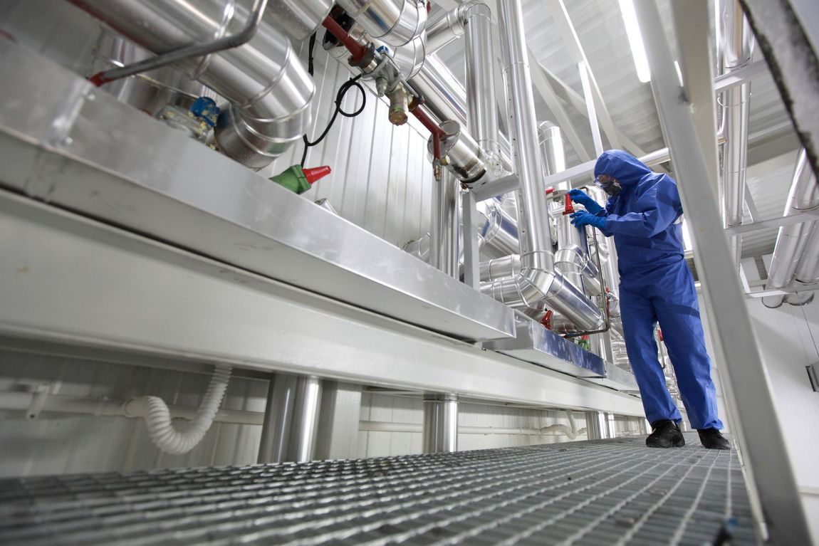 Un uomo vestito di blu sta lavorando sui tubi in una fabbrica.