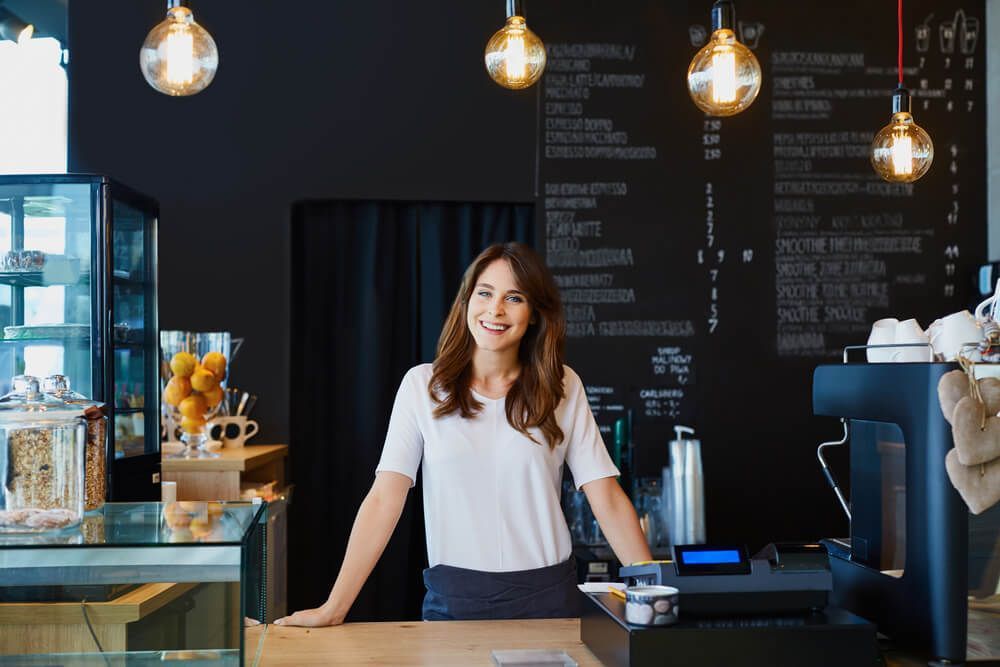A Woman Is Standing Behind a Counter in A Coffee Shop — Marks Financial Group in  Toowoomba City, QLD