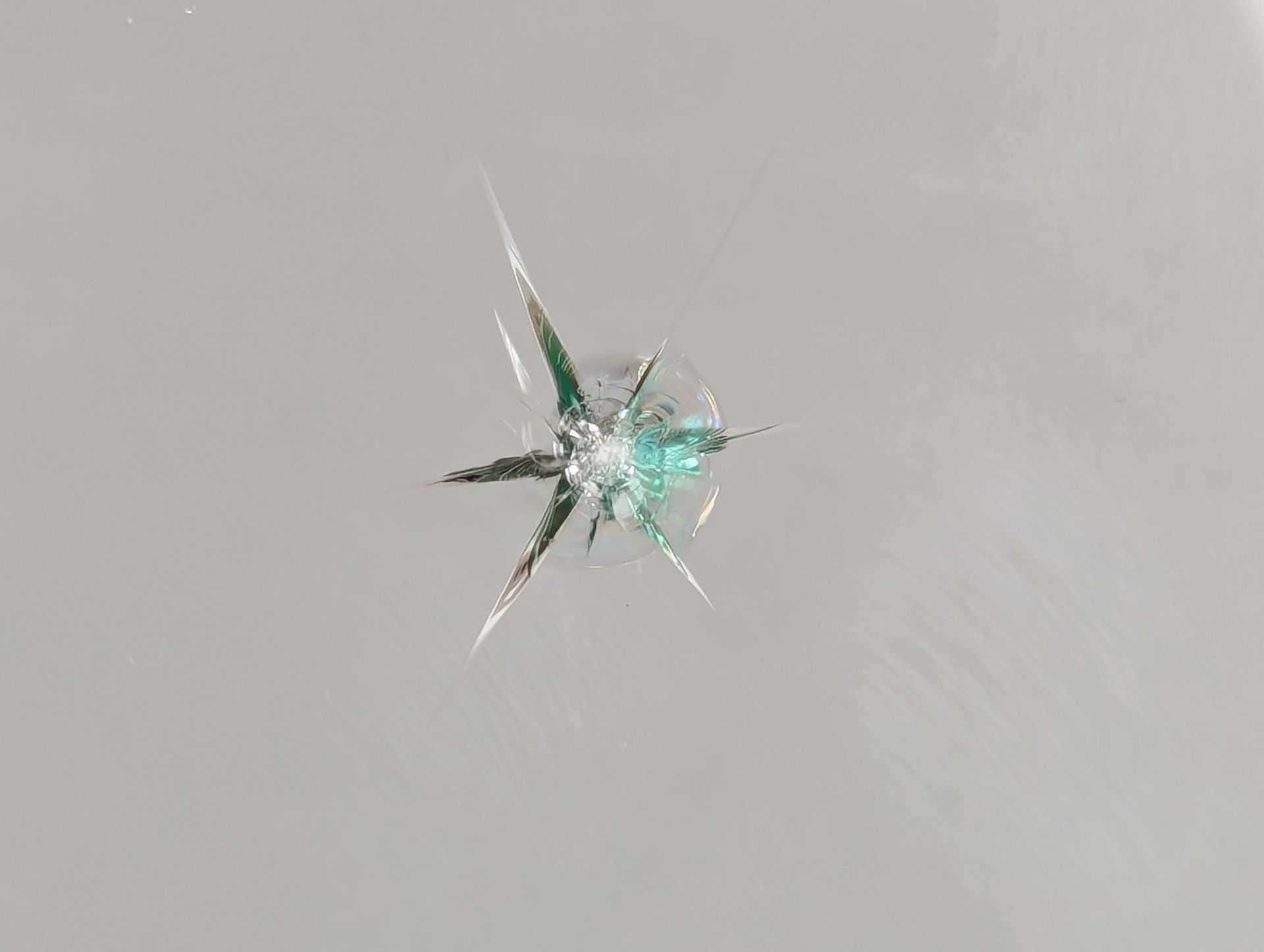 A close up of a broken glass window with a person walking in the background.
