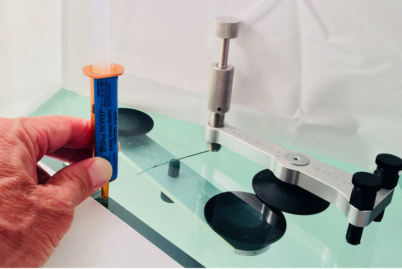 A person is holding a tube of adhesive in their hand