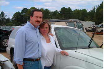 A man and woman standing next to a white SUV that they repaired a 12 inch windshied crack that was in a rollover crash