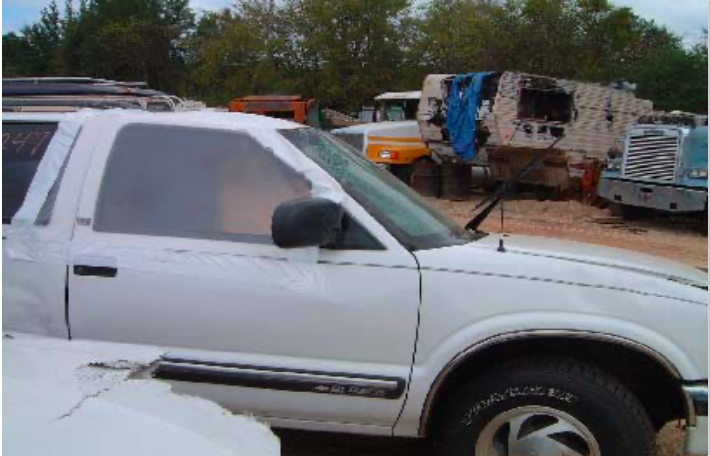 A white truck is parked in a lot with other trucks