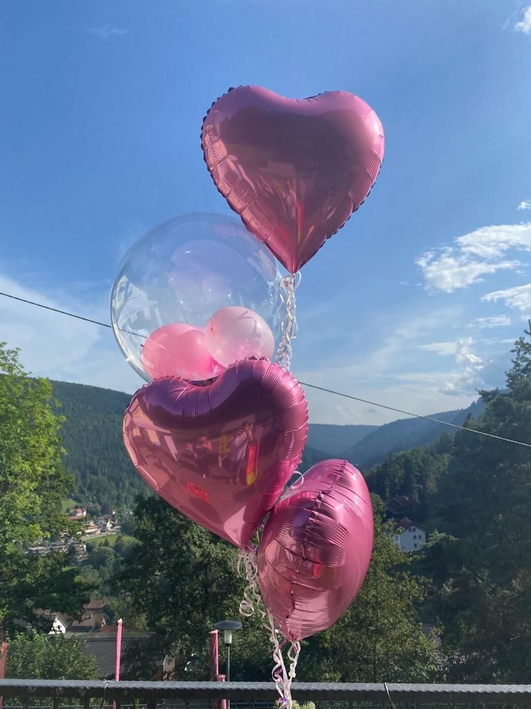 Ein Bündel rosa herzförmiger Luftballons, die an einer Kette hängen