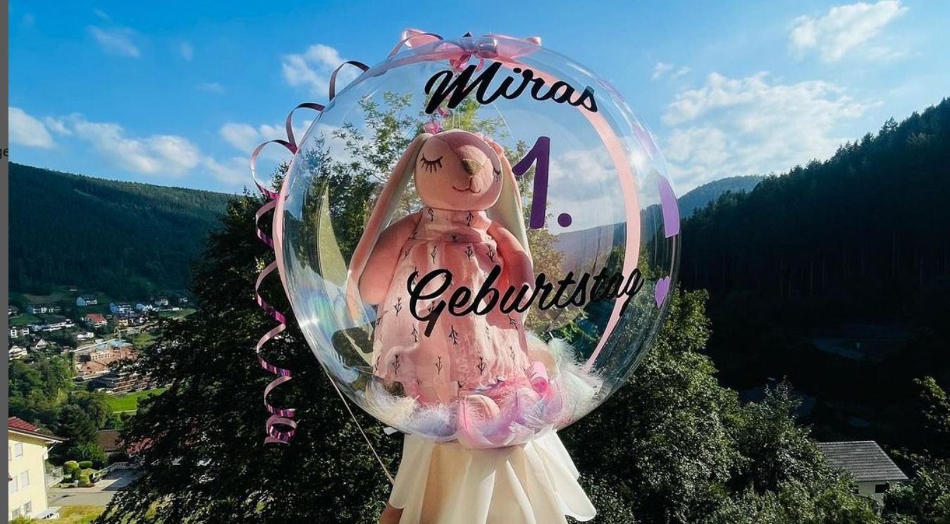 Ein Mädchen steht in einem Ballon, in dem sich ein Teddybär befindet.