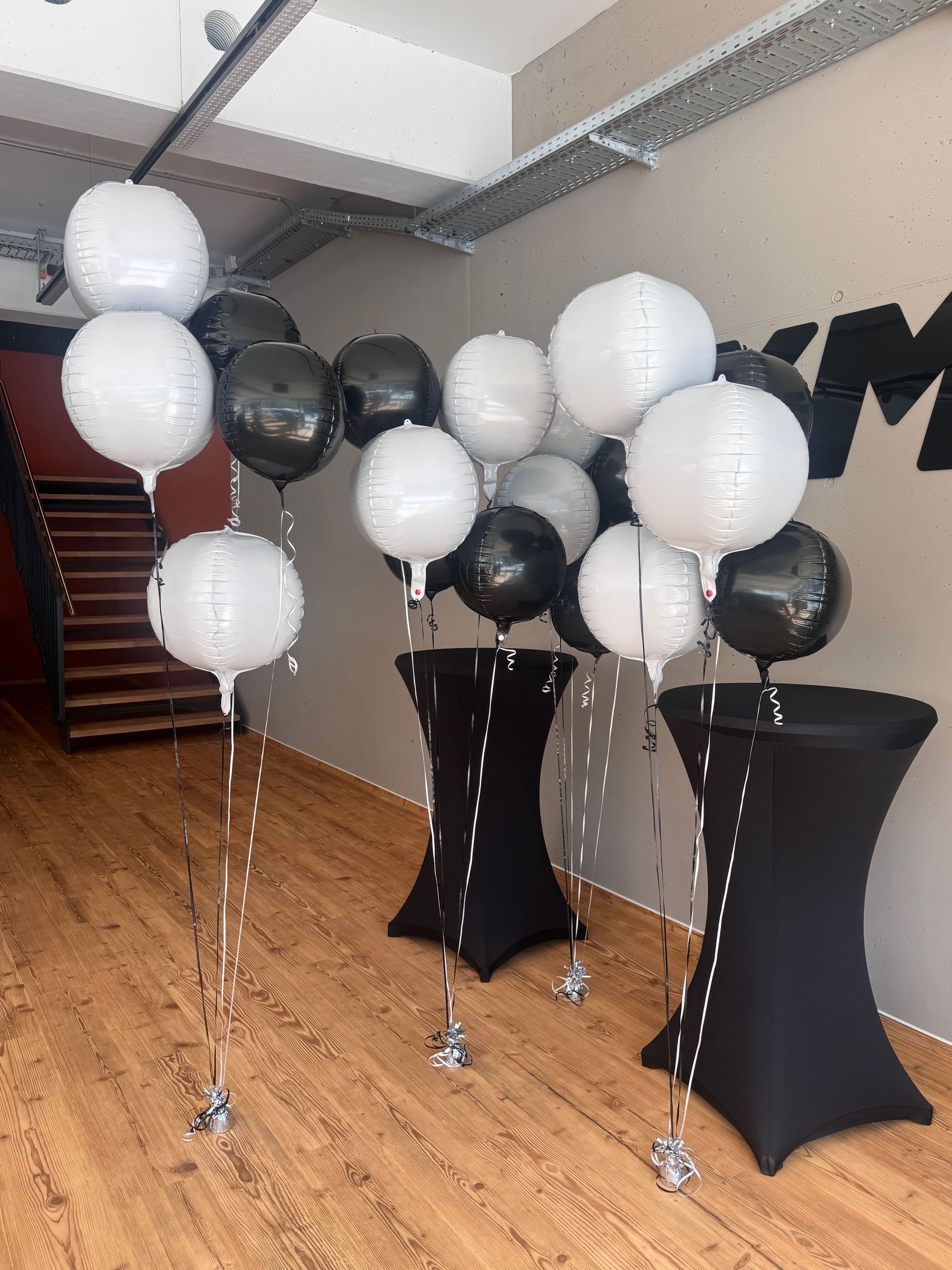 Ein Ballonbogen in Rosa, Weiß und Silber umrahmt einen Türrahmen.