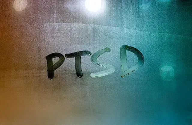 The word ptsd is written on a foggy window.