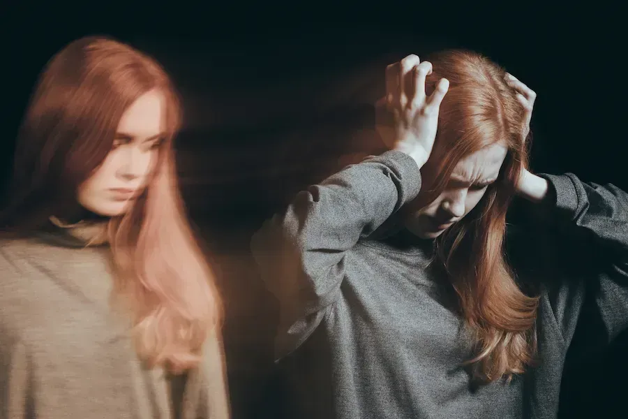 Two women are standing next to each other and one is covering her ears with her hands.