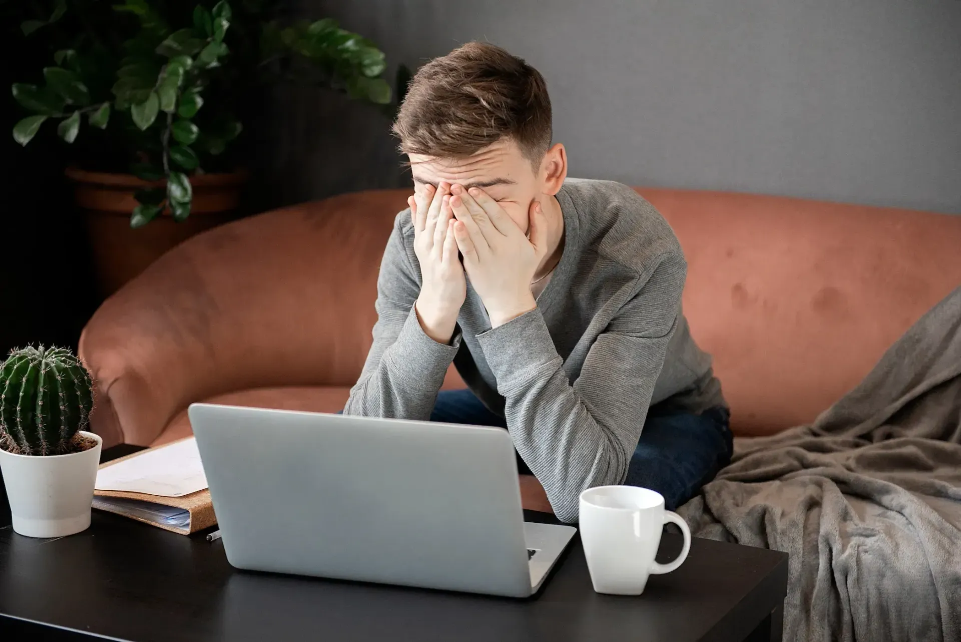 A man is sitting on a couch using a laptop computer.