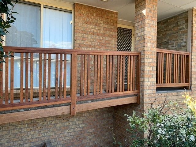 A wooden balcony with a brick wall in the background