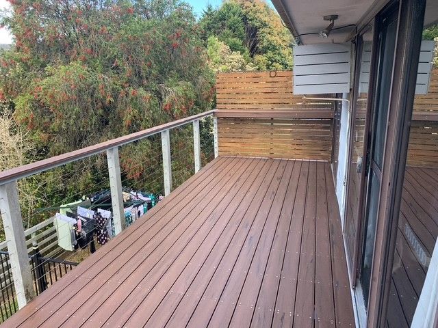 A large deck with a wooden railing and sliding glass doors.
