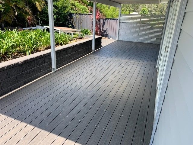 A gray deck with a white fence in the background