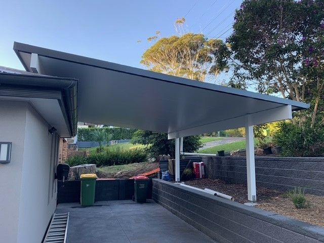 A carport with a roof and a ladder in front of a house.