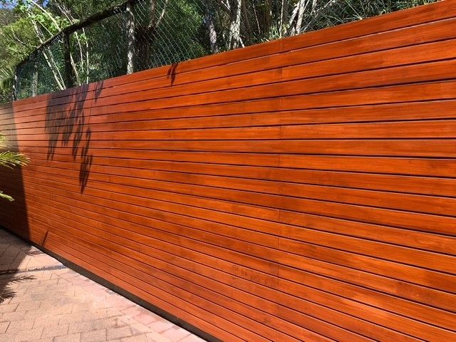 A close up of a wooden fence with trees in the background.