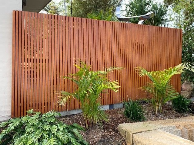 A wooden fence is surrounded by plants in a garden.