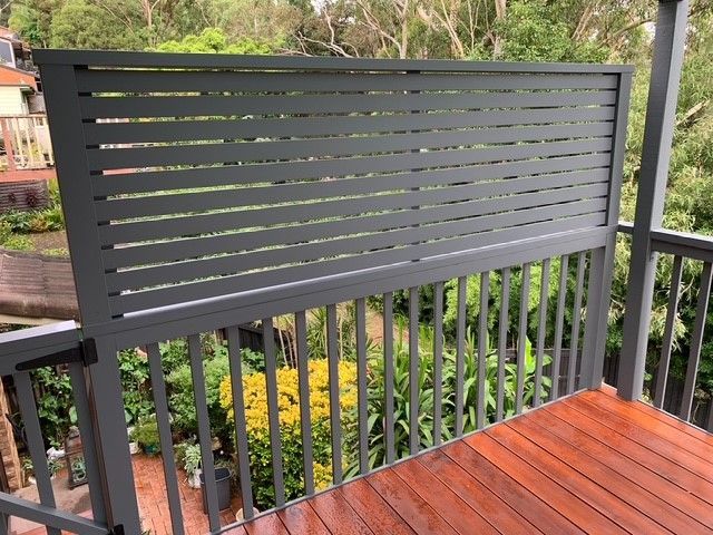A balcony with a fence and a wooden deck.