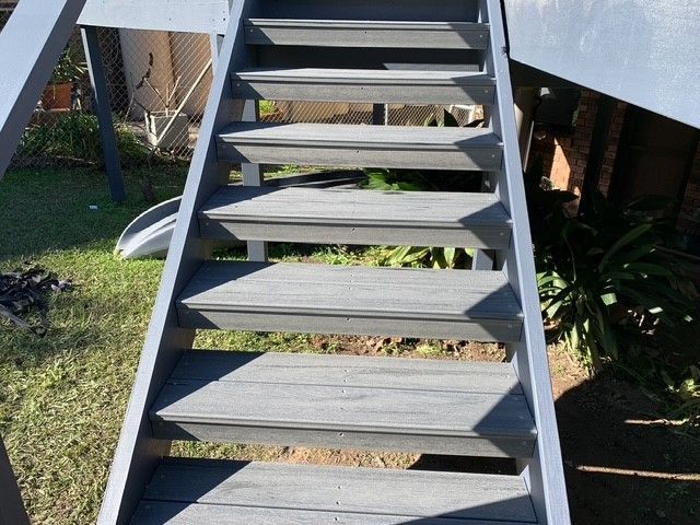 A set of gray wooden stairs leading up to a house