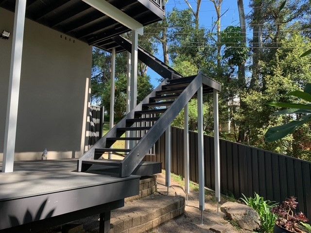 A set of stairs leading up to a deck with trees in the background