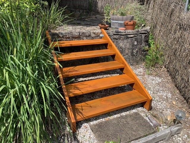 A set of wooden stairs leading up to a stone wall in a garden.
