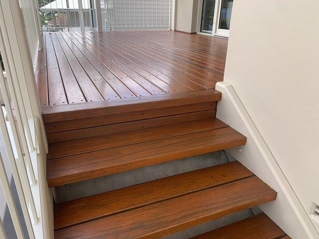 A set of wooden stairs leading up to a wooden deck.