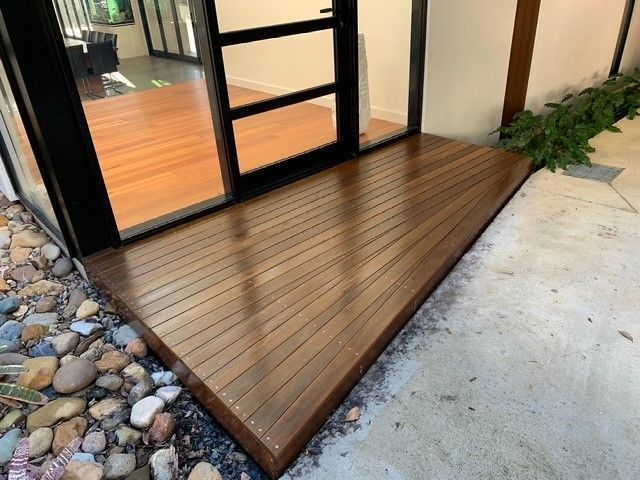 A wooden deck is next to a glass door