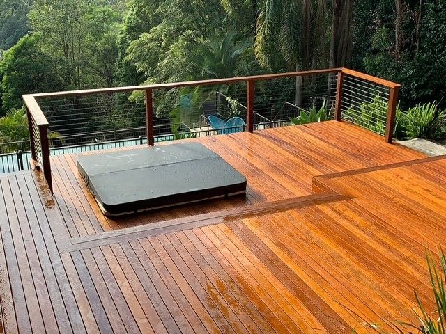 A wooden deck with a hot tub on top of it.