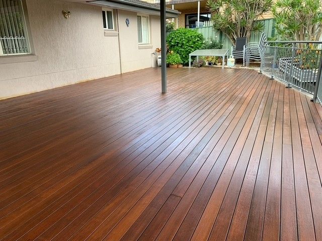 A large wooden deck is sitting in front of a house.