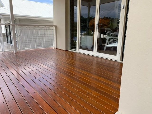 A wooden deck with a white railing and sliding glass doors