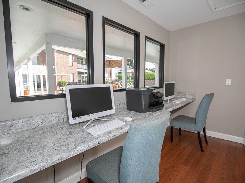 Community computer station with desks, chairs, a printer, and large windows.
