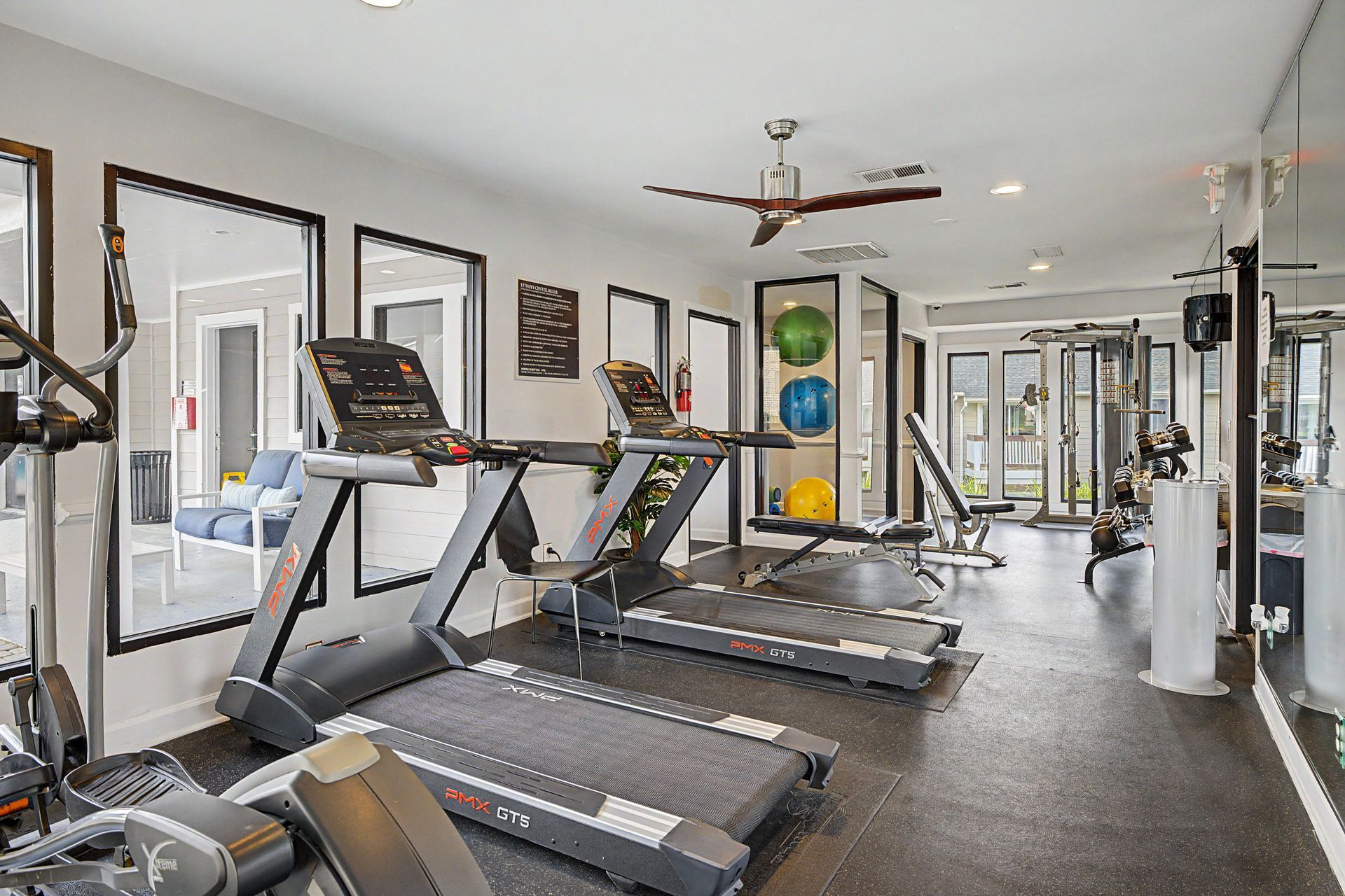Indoor gym with treadmills, mirrors, and exercise equipment on a dark floor