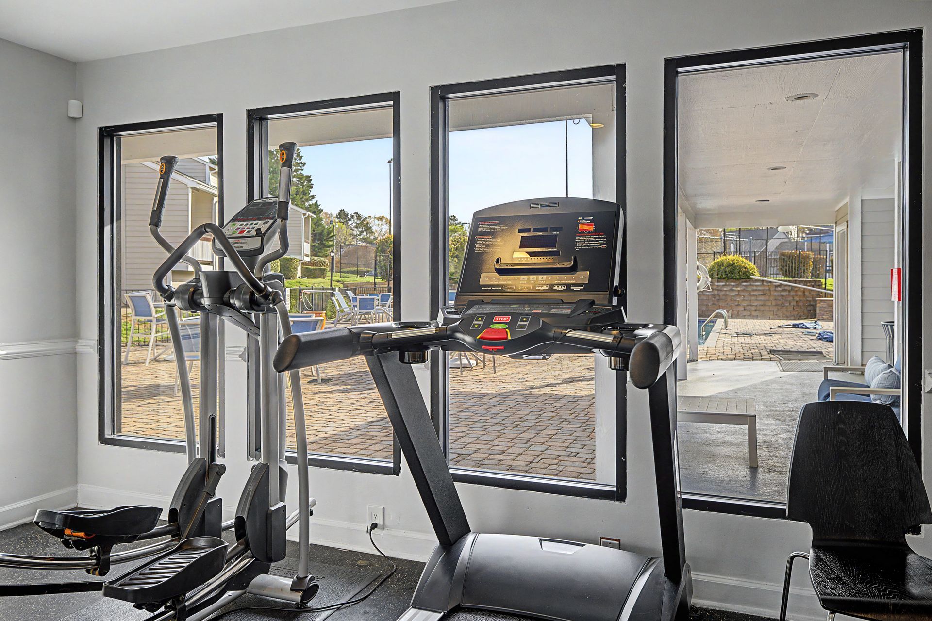 Gym room with treadmill, elliptical, and wall-mounted TV in front of large windows