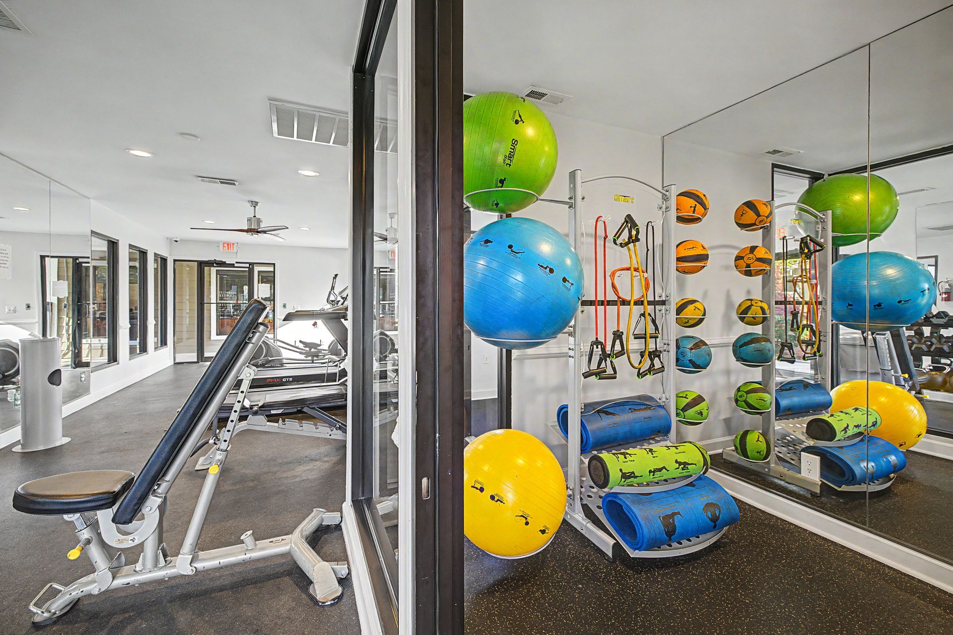 Gym with exercise machines and colorful stability balls in a mirrored workout area