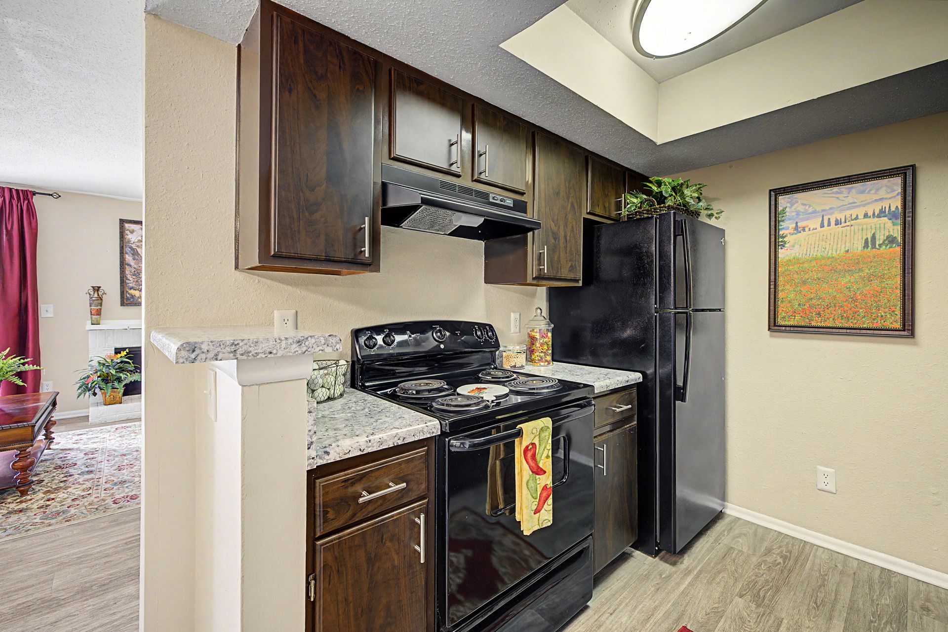 Compact kitchen with black appliances, wood cabinets, granite counters, and a black refrigerator.