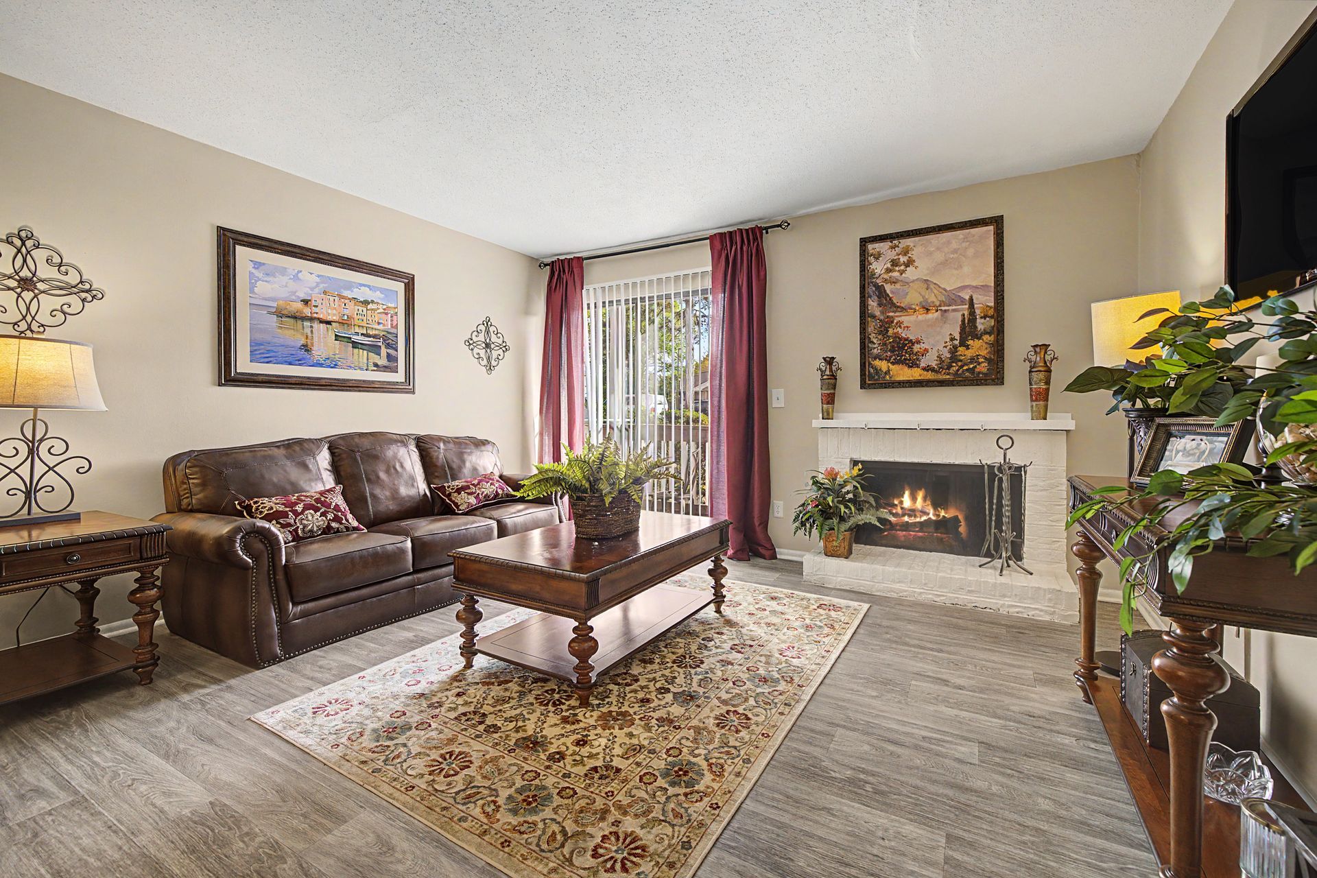 Cozy living room with brown sofa, fireplace, patterned rug, and floral curtains