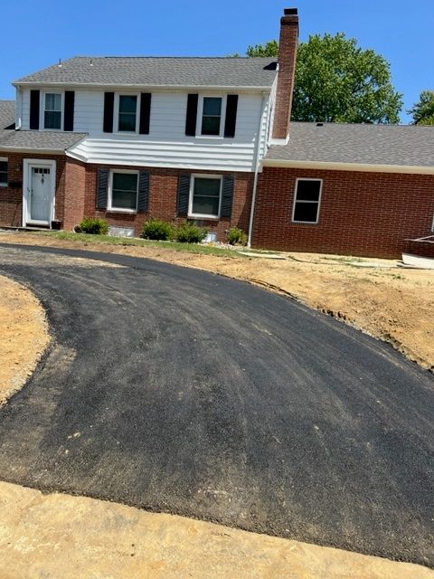 Two-story brick house with a newly paved asphalt driveway.