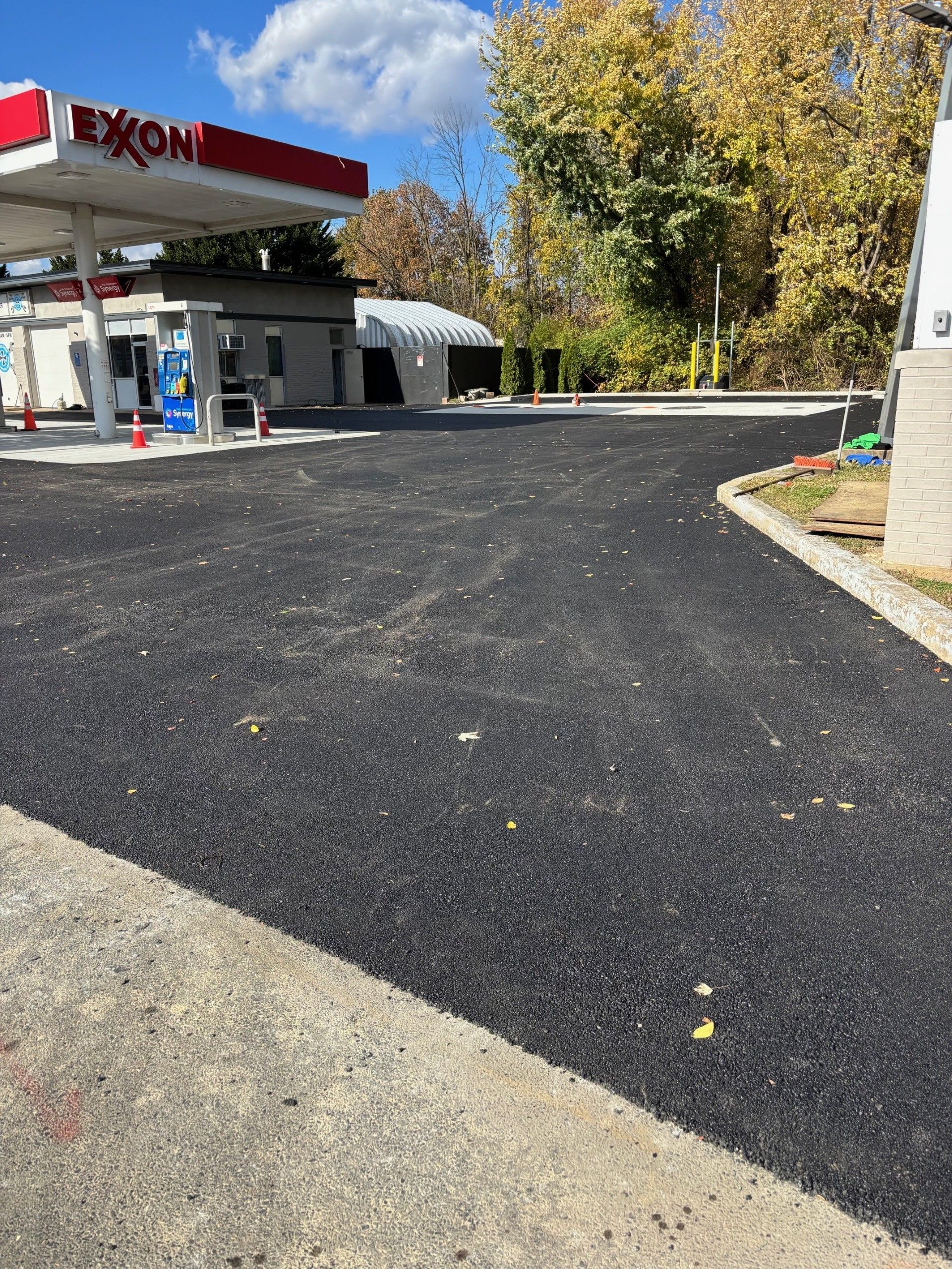 Newly paved asphalt driveway at an Exxon gas station with a building in the background.