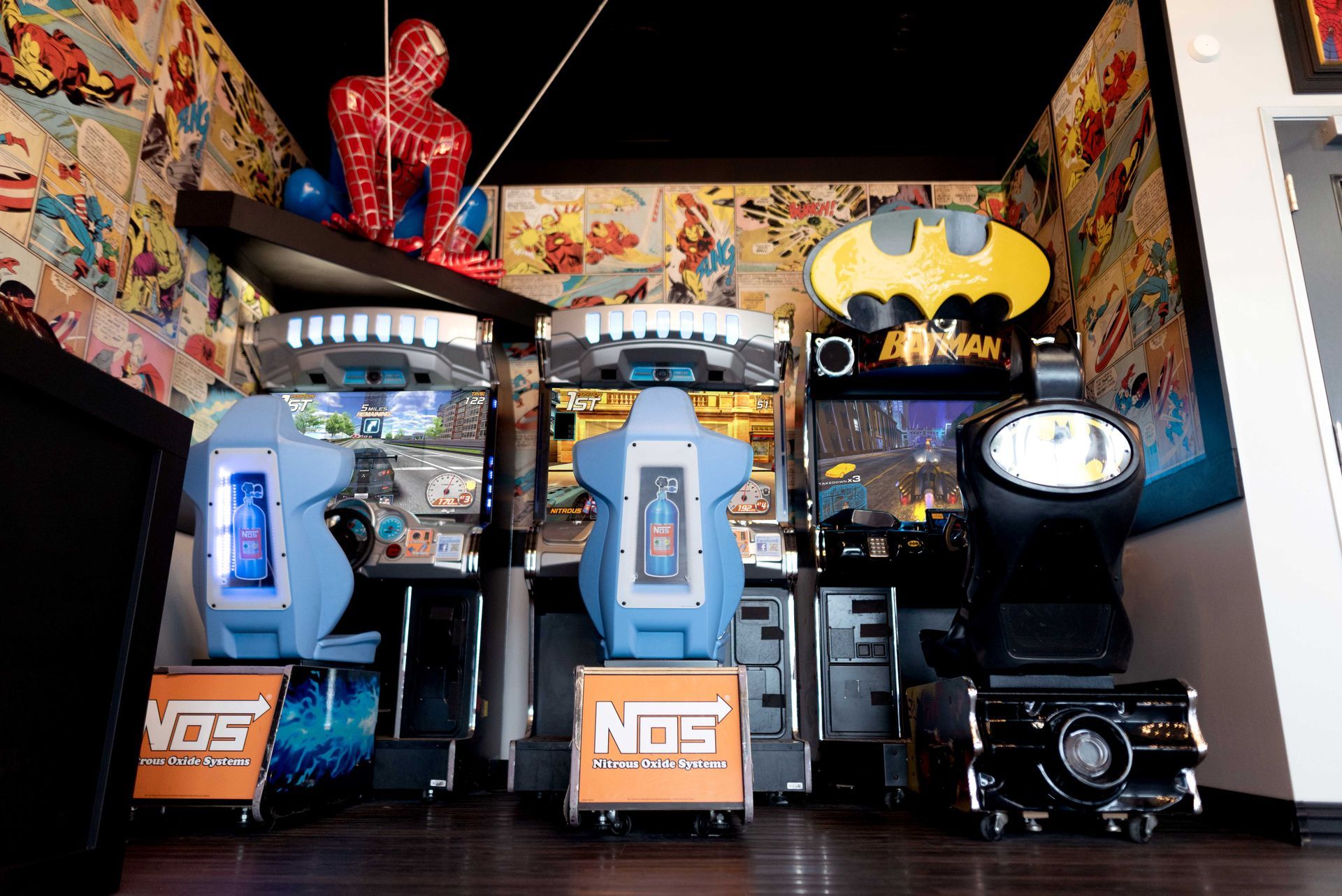 Arcade with three basketball shooting games, colorful comic-themed decor, and a Batman logo sign