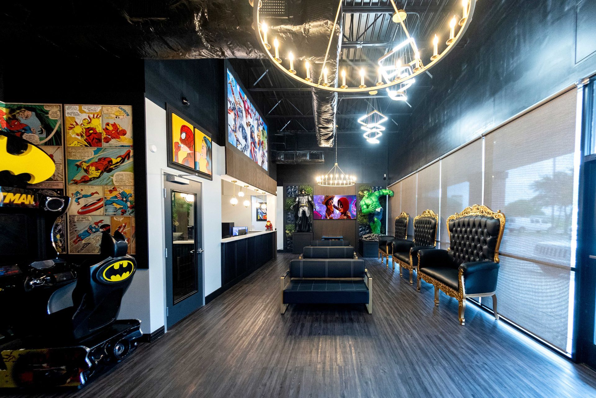 Modern salon interior with black couches, wall art, and a bright chandelier