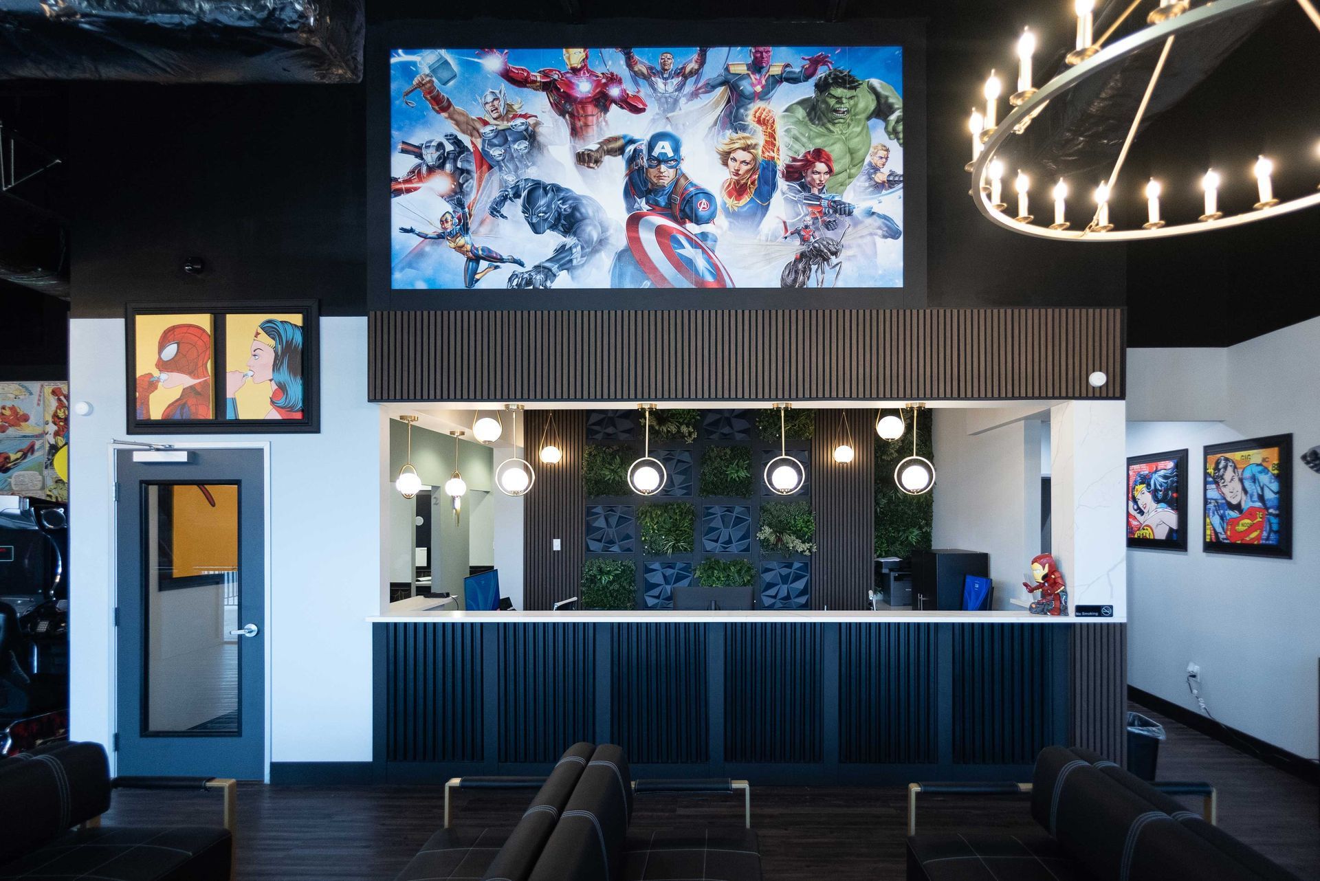 Bright lobby with superhero mural, reception desk, pendant lights, and seating area