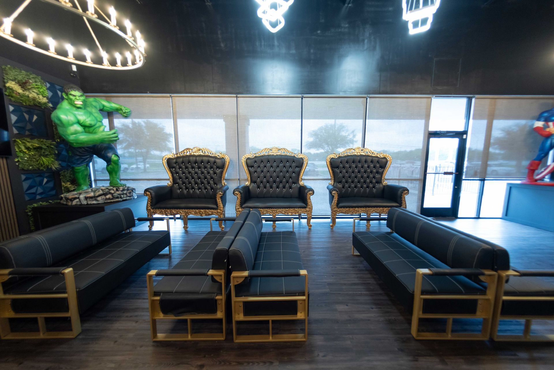 Modern lounge with black couches, gold chairs, and a glossy floor under bright ceiling lights