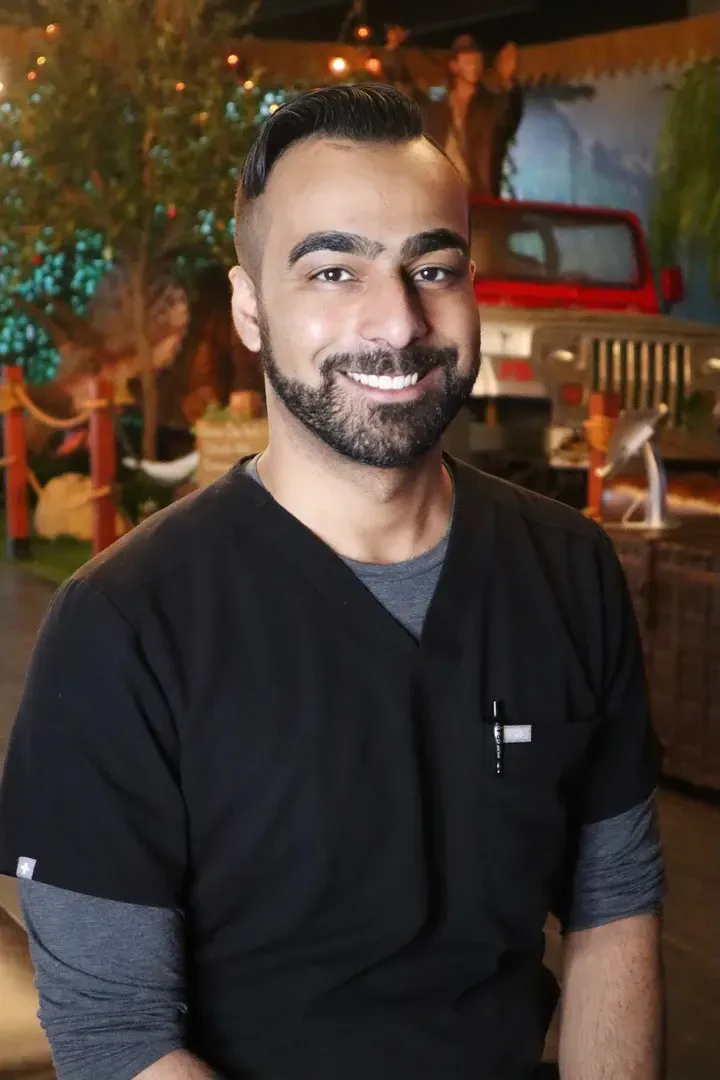 Smiling person in black scrubs standing indoors at a warmly lit event venue
