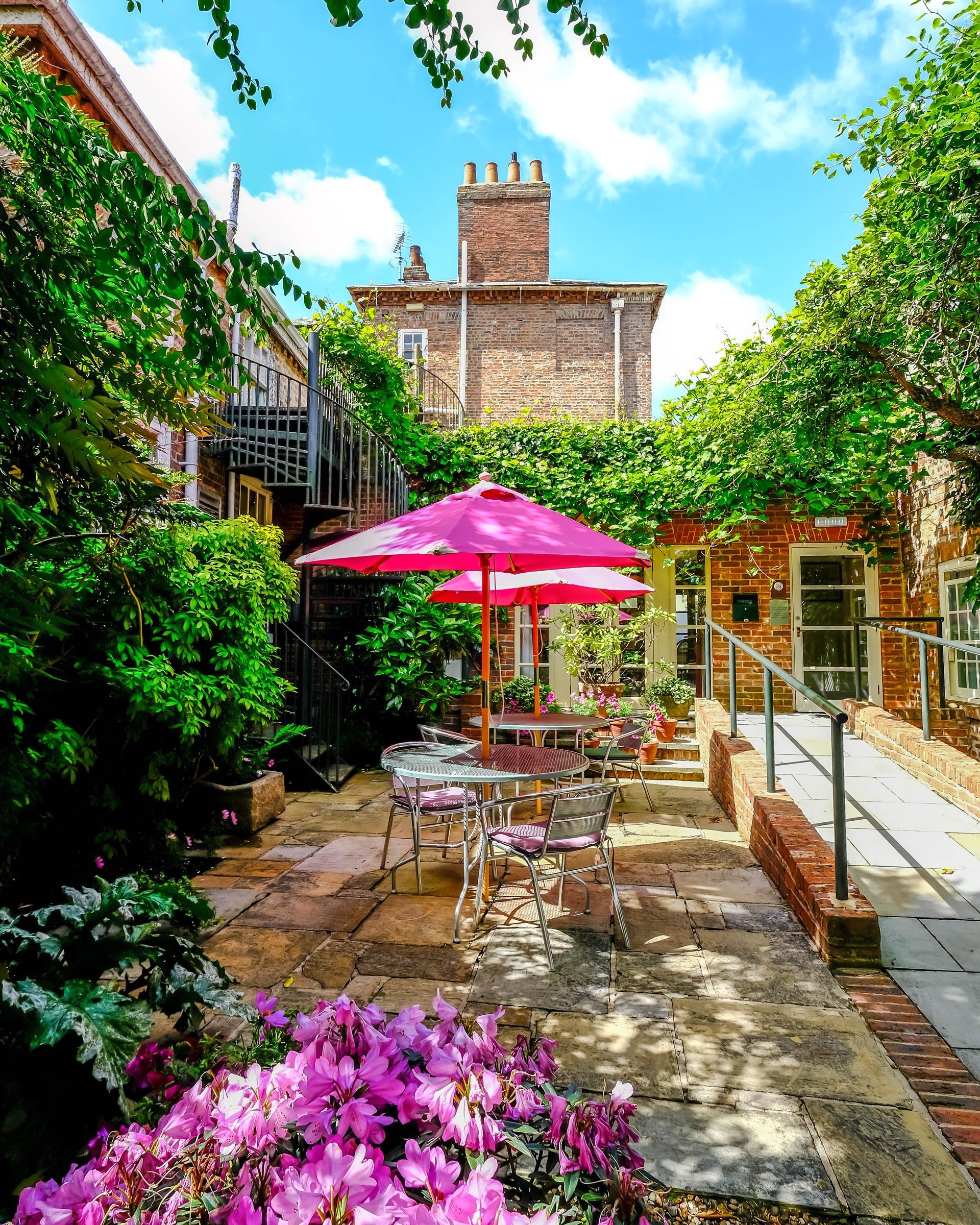 A patio with tables and chairs and pink umbrellas