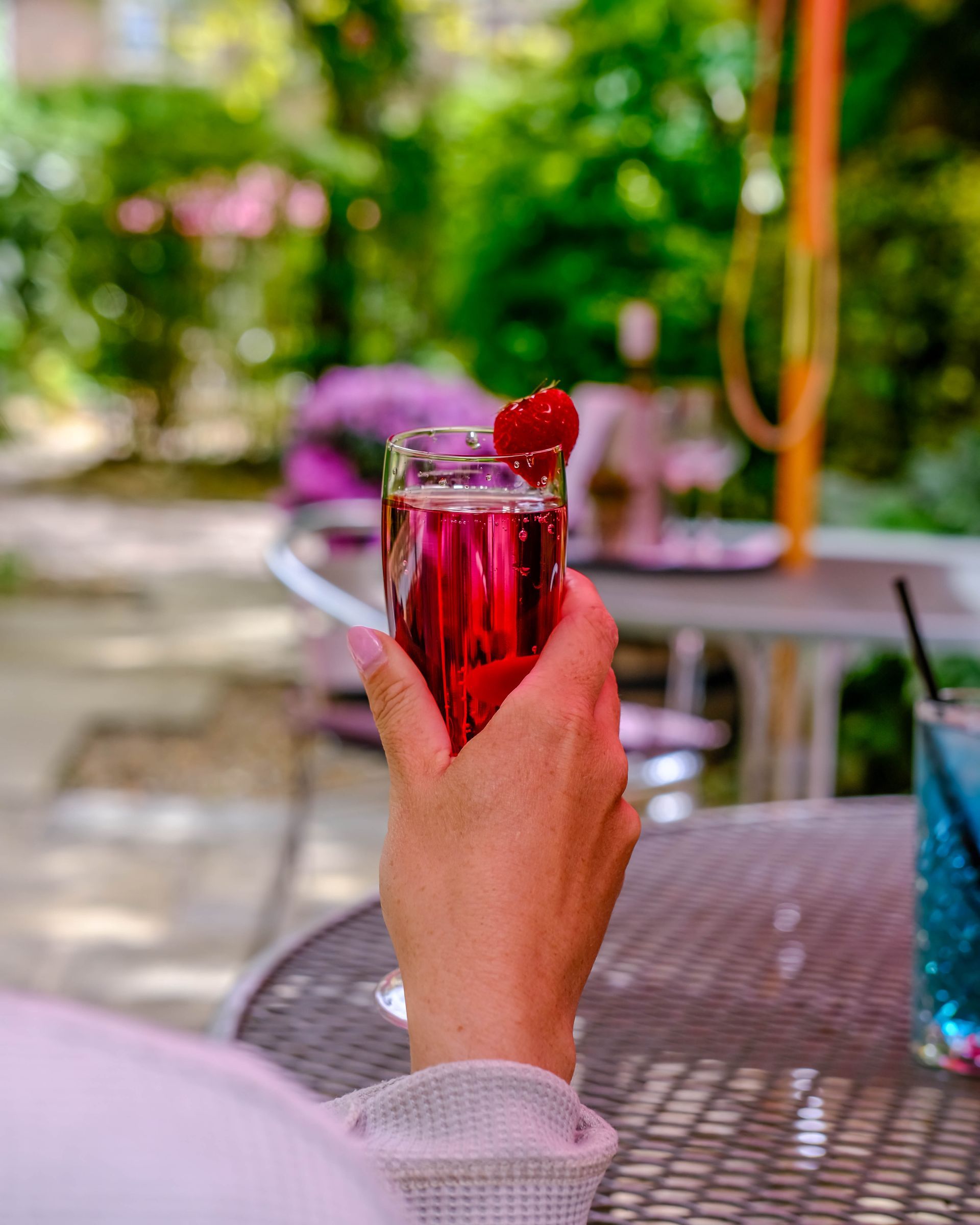 A person is holding a glass of wine with a cherry in it.