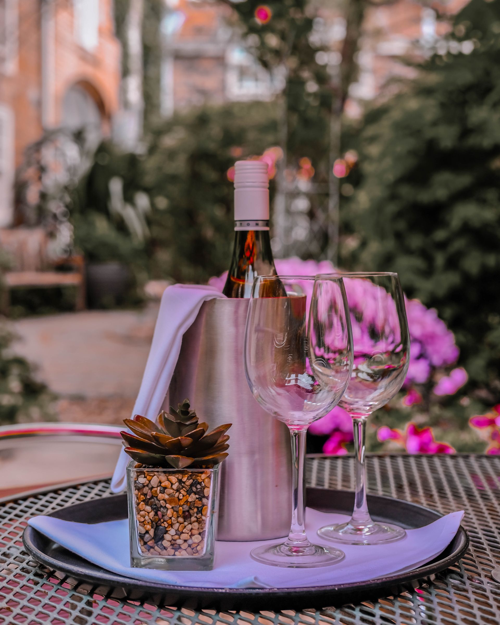 A bottle of wine and two wine glasses are on a tray on a table.