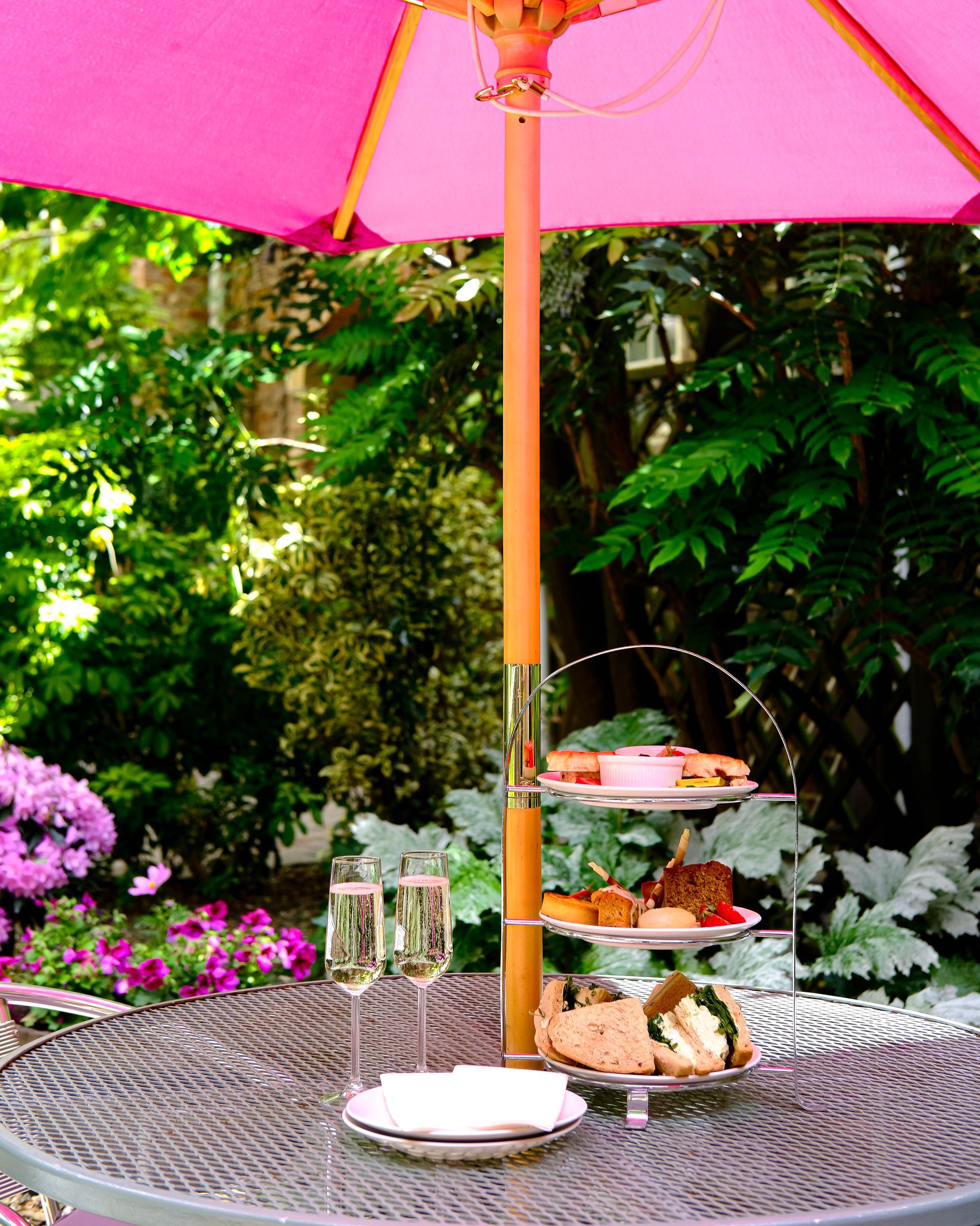 A table with a pink umbrella and plates of food on it