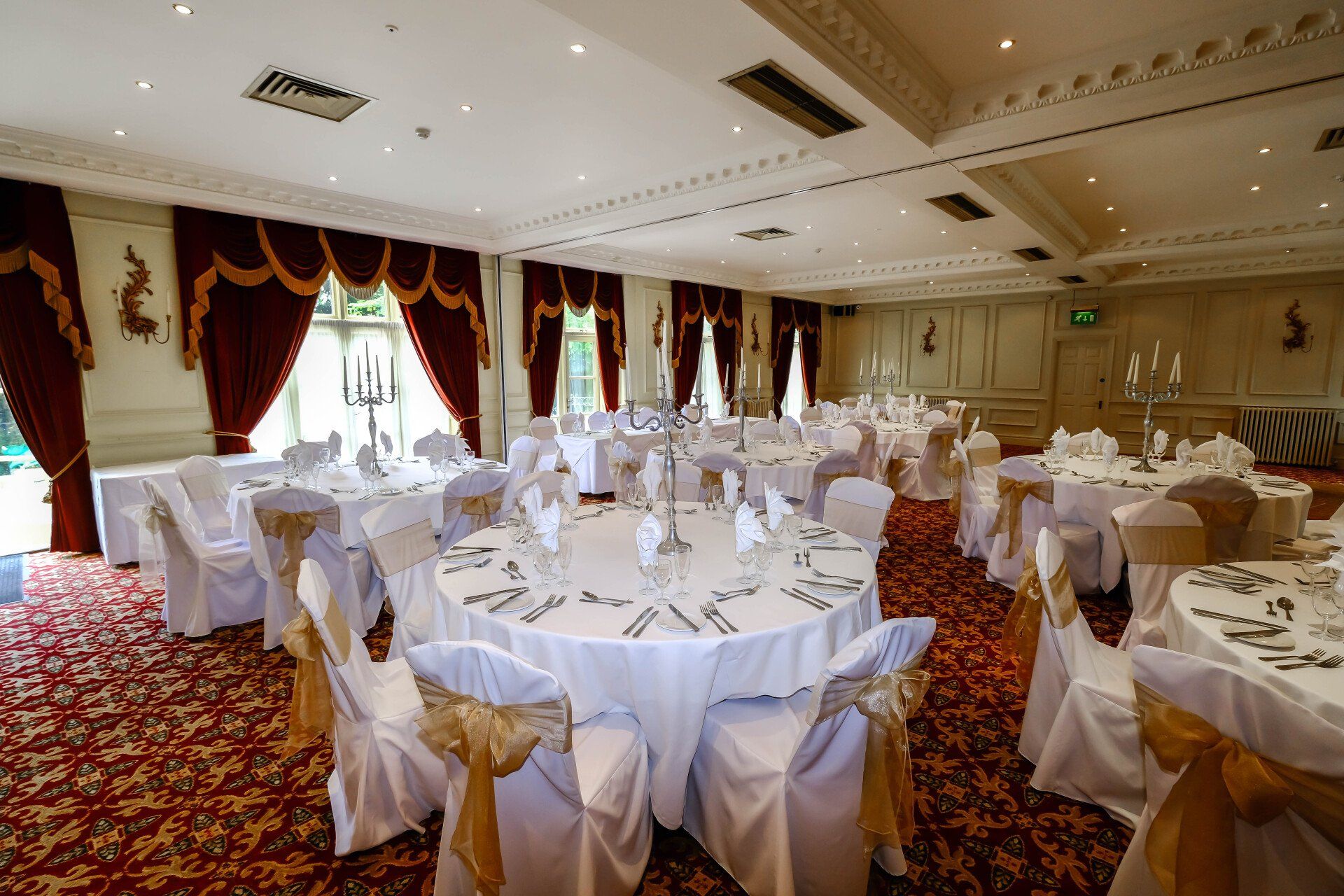 A large room with tables and chairs set up for a wedding reception.